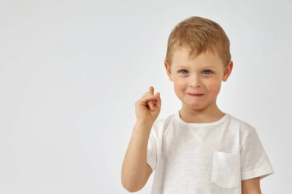 Un chico con una cara graciosa señala su dedo sobre un fondo blanco — Foto de Stock