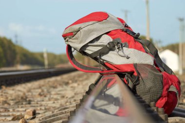 Çam ormanındaki demiryolunda kırmızı sırt çantası. Seyahat kavramı