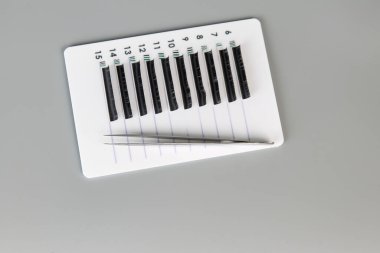 Gri arka planda takma kirpikli ve cımbızlı tablet. Kirpik uzantıları için kozmetik aksesuarlar