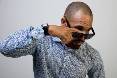 Siyah güneş gözlüklü havalı Latin adam beyaz arka plandaki fotokopi odasına dikkatlice bakıyor.