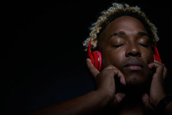 Un hombre afroamericano disfruta de la música con auriculares rojos — Foto de Stock