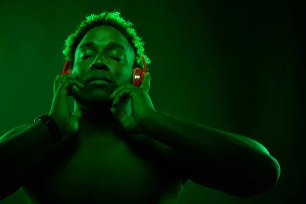 Hombre negro disfruta de la música en auriculares rojos — Foto de Stock