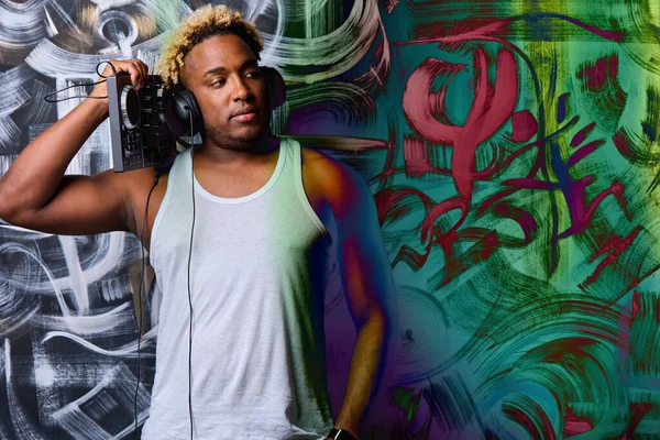 Un DJ afroamericano con una consola de DJ en un club contra una pared con graffiti — Foto de Stock