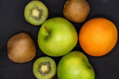 Karanlık bir arka planda meyve fotoğrafı. Portakal, elma, kivi.