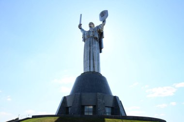 KYIV, UKRAINE - 10 Nisan 2019: Anavatanın tarihi müzedeki SSCB 'den bir kılıç ve bir tahta parçasıyla dikilmiş anıtı. Bulutlu gökyüzünün arka planında büyük bir heykel