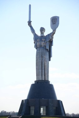 KYIV, UKRAINE - 10 Nisan 2019: Anavatanın tarihi müzedeki SSCB 'den bir kılıç ve bir tahta parçasıyla dikilmiş anıtı. Bulutlu gökyüzünün arka planında büyük bir heykel