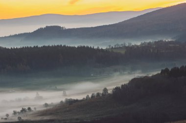 Sakin kırsal alanlarda sisli bir sabah manzarası ve uzak evler. Sakin bir kır manzarası sisli bir sabahı tarlalarda yuvarlanırken yakalıyor. Uzaktan bakan evler sislerin arasından sakin ve huzurlu bir atmosfer yaratıyor.. 