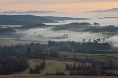 Sakin kırsal alanlarda sisli bir sabah manzarası ve uzak evler. Sakin bir kır manzarası sisli bir sabahı tarlalarda yuvarlanırken yakalıyor. Uzaktan bakan evler sislerin arasından sakin ve huzurlu bir atmosfer yaratıyor.. 
