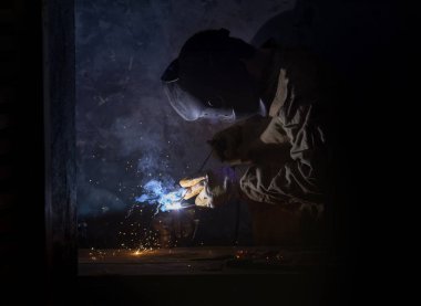 Kaynak makinası metalin üzerine elektrik kaynaklarıyla kaynak yapıyor.