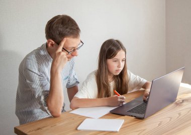 Babam ve genç bir kız dizüstü bilgisayarda zor bir ödev yapıyorlar. Yüzleri gergin. Mesafe öğrenme kavramı. Samimi boş zaman