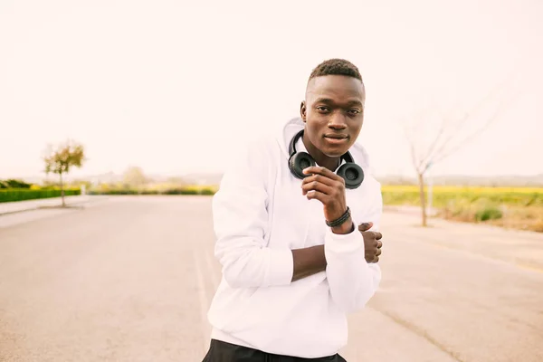 Afro saçlı, beyaz kazak, siyah pantolon ve kablosuz kulaklık takmış, sokaklarda dans eden Afro Amerikalı genç bir adam. Mutlu ve neşeli tavır