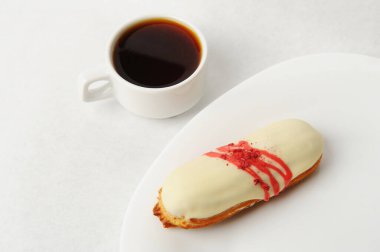 Beyaz bir tabakta kremalı çilekli pasta ile iştah açıcı. Bir fincan kahve, saf beyaz arka plan.