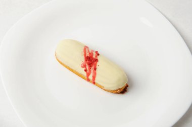 Vanilya kremalı ve beyaz tabakta çilek soslu Fransız tatlısı. Zarif servis biçimi