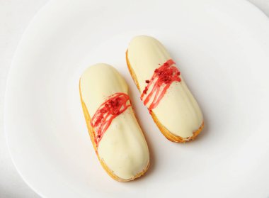 Vanilya kremalı ve beyaz tabakta çilek soslu Fransız tatlısı. Zarif servis biçimi