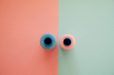 Geometrik iki renkli arka planda mavi ve pembe dikiş iplikleri. Tekstil ya da el işi kavramı