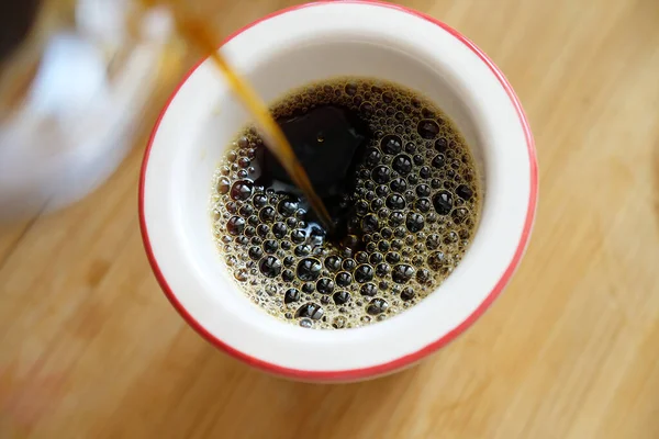 Verter el café negro recién hecho sobre el filtro en primer plano de la taza. — Foto de Stock