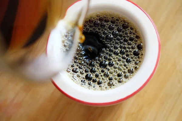 Verter el café negro recién hecho sobre el filtro en primer plano de la taza. — Foto de Stock