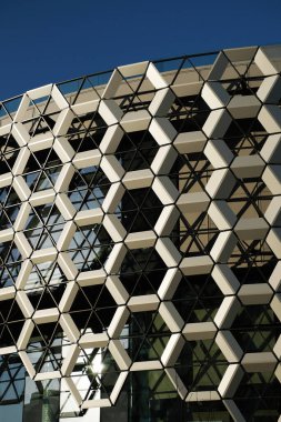 Facade of a modern shopping center. A wall composed of honeycombs hexagons. Contemporary architecture, exterior. Blue sky