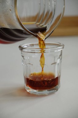 Özel kahve konsepti. Siyah filtre kahve cam bardağa cam sürahide yakın planda dökülür.