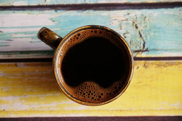 Café negro caliente fresco en taza de café expreso de cerámica. Vista superior, primer plano. Fondo de madera de color llano — Foto de Stock