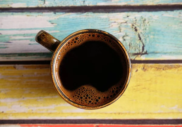Café negro caliente fresco en taza de café expreso de cerámica. Vista superior, primer plano. Fondo de madera de color llano —  Fotos de Stock