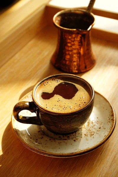 Φρεσκοψημένος ζεστός τούρκικος καφές σε κεραμικό κύπελλο. Χαλκός cezve. Δίσκος από μπαμπού. Φως ημέρας, σκιές. — Φωτογραφία Αρχείου