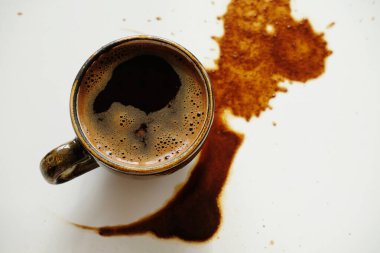 Beyaz arka planda dökülmüş kahve lekeleri üzerine bir fincan espresso.