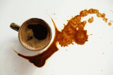 Beyaz arka planda dökülmüş kahve lekeleri üzerine bir fincan espresso.