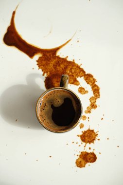 Beyaz arka planda dökülmüş kahve lekeleri üzerine bir fincan espresso.