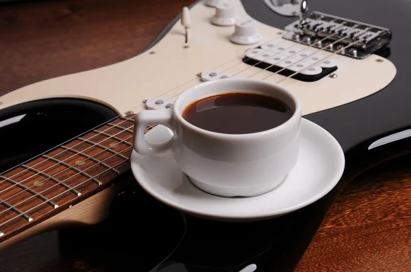 Xícara de café preto está na guitarra elétrica — Fotografia de Stock