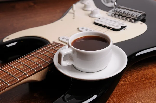 Xícara branca de café preto está na guitarra elétrica — Fotografia de Stock