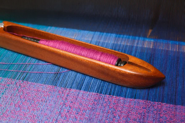 Weaving shuttle with thread on the blue warp — Stock Photo, Image