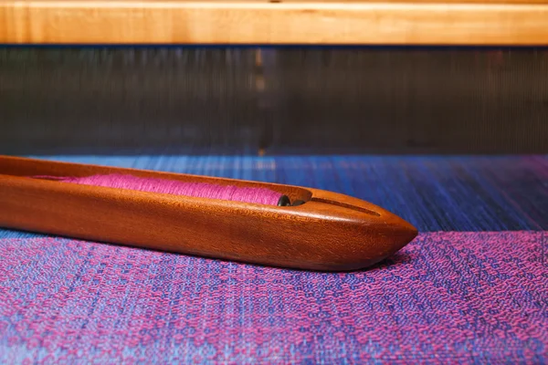 Weaving shuttle with thread on the blue warp — Stock Photo, Image