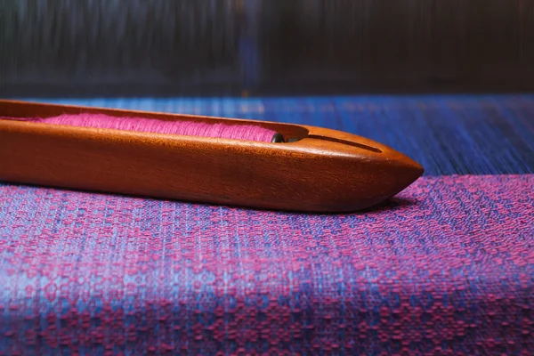 Weaving shuttle with thread on the blue warp — Stock Photo, Image