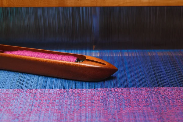 Weaving shuttle with thread on the blue warp — Stock Photo, Image