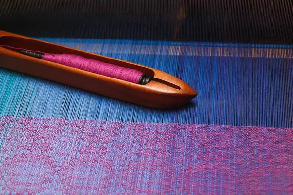 Weaving shuttle with thread on the blue warp — Stock Photo, Image