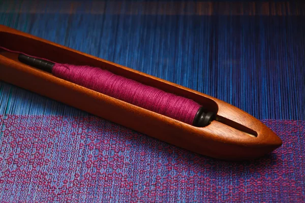 Navetta di tessitura con filo sull'ordito blu — Foto Stock