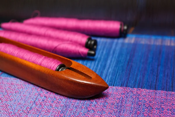 Navetta per tessitura con bobine di filo sull'ordito blu — Foto Stock
