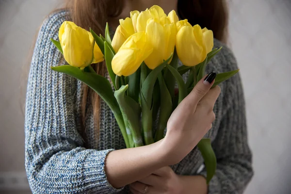 A young woman holding a bunch of yellow tulips, close-up — Stock Photo, Image