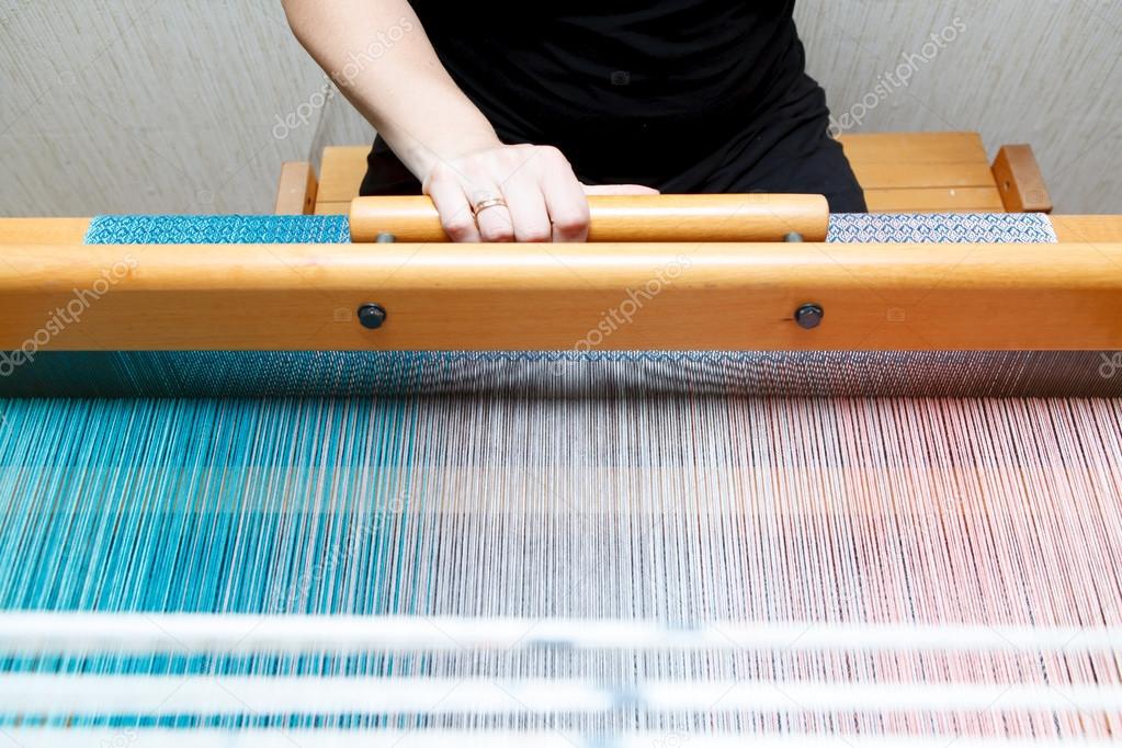 Hands of a woman who weaves on a loom