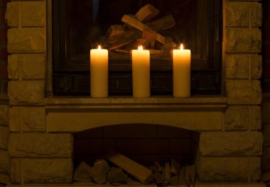 Şöminenin üzerinde duran beyaz büyük mumlar. 