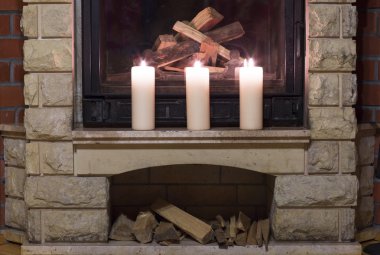 Şöminenin üzerinde duran beyaz büyük mumlar. 