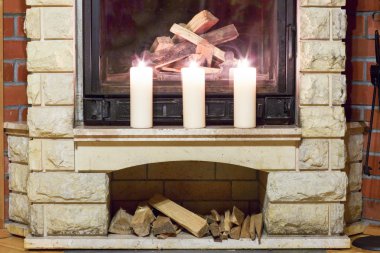 Şöminenin üzerinde duran beyaz büyük mumlar. 