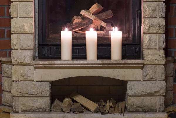 Şöminenin üzerinde duran beyaz büyük mumlar. 