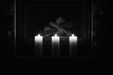 Şöminenin üzerinde duran beyaz büyük mumlar.