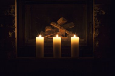 Şöminenin üzerinde duran beyaz büyük mumlar.