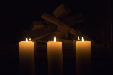 Şöminenin üzerinde duran beyaz büyük mumlar.