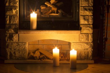 Şöminenin üzerinde duran beyaz büyük mumlar.