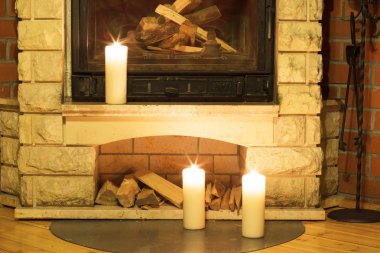 Şöminenin üzerinde duran beyaz büyük mumlar.