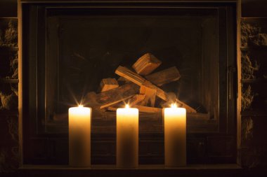 Şöminenin üzerinde duran beyaz büyük mumlar.